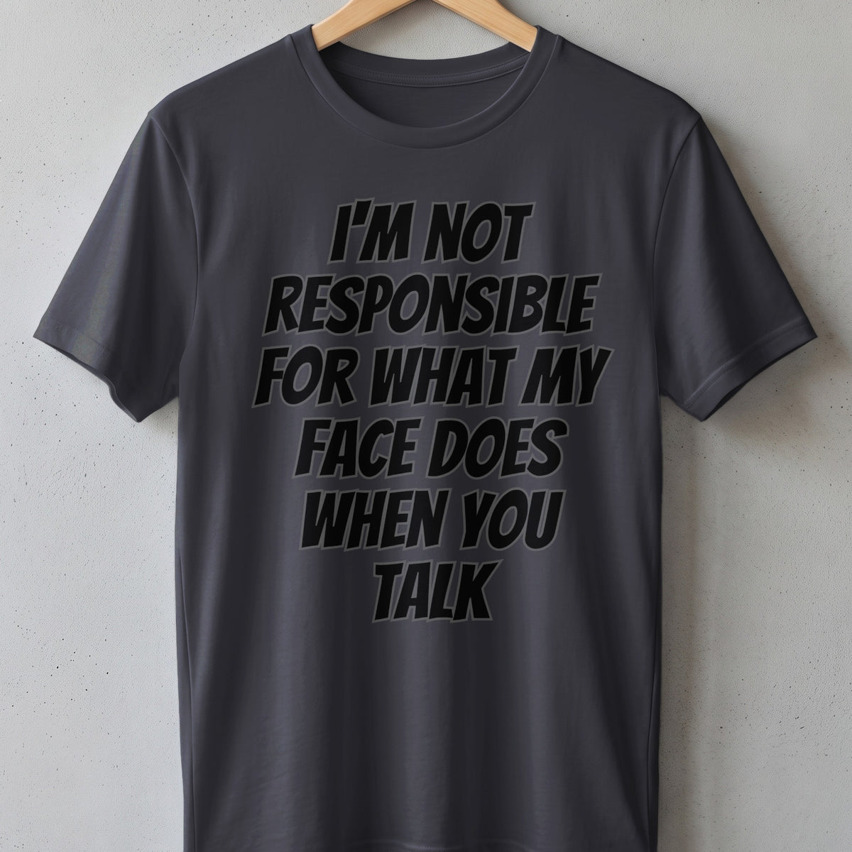 Dark gray t-shirt with black text that reads "I'M NOT RESPONSIBLE FOR WHAT MY FACE DOES WHEN YOU TALK".