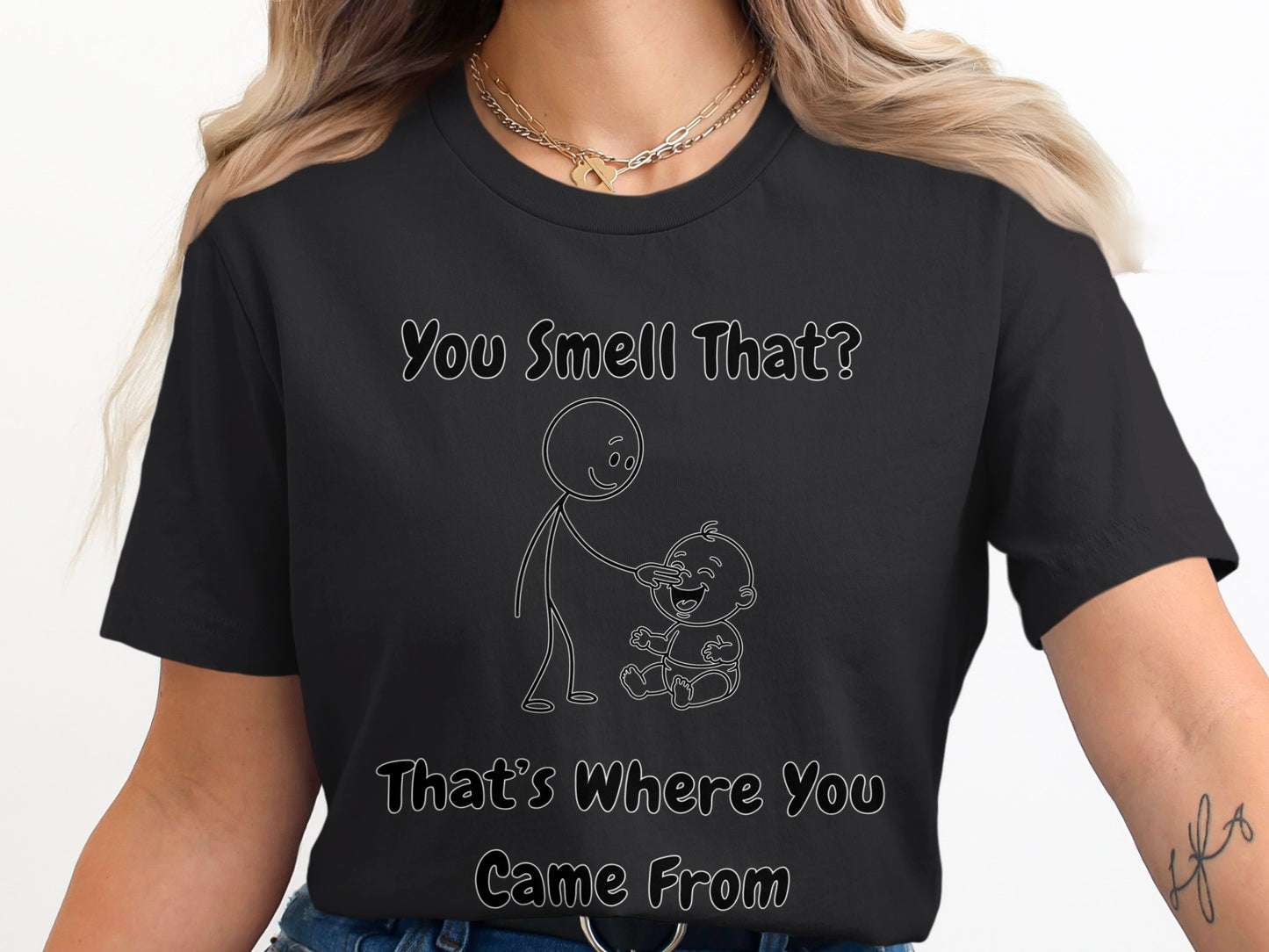 Black t-shirt with line drawing of stick figure touching baby's nose. Text reads "You Smell That? That's Where You Came From".