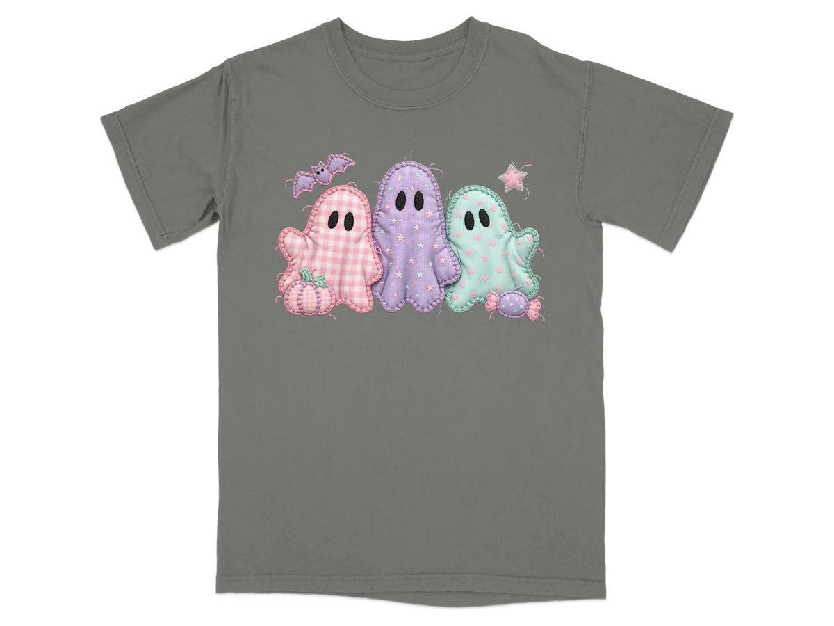 Three pastel ghosts with Halloween motifs on a gray t-shirt.