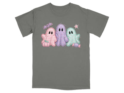 Three pastel ghosts with Halloween motifs on a gray t-shirt.