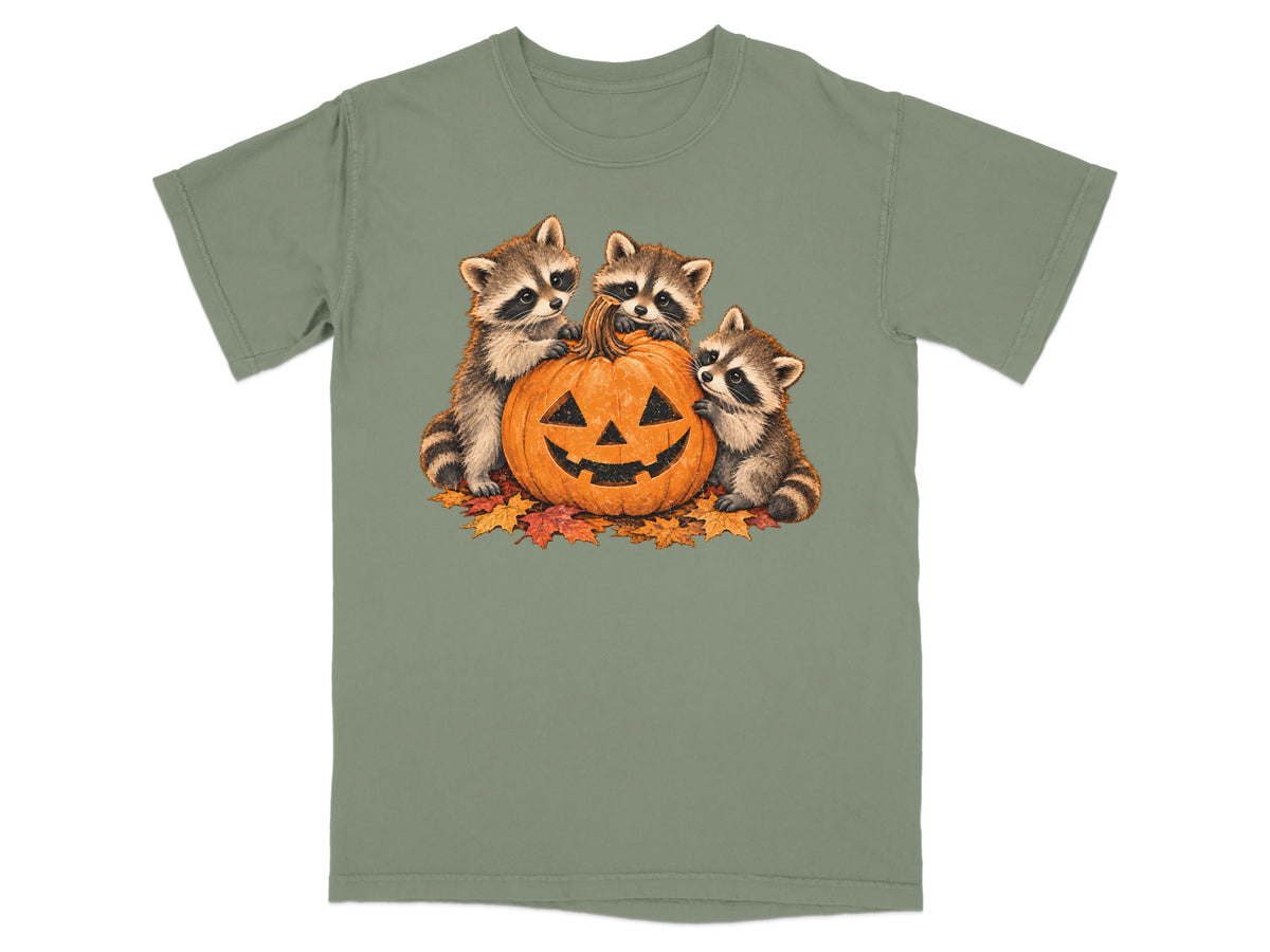 Three baby raccoons surround a jack-o'-lantern on a bed of autumn leaves.