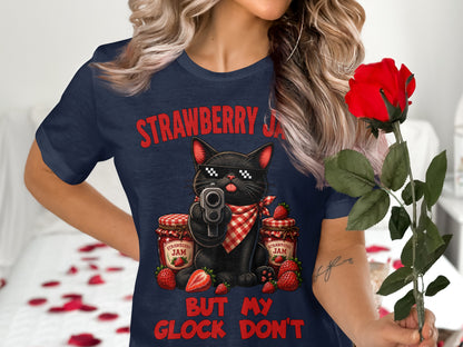 T-shirt graphic of a black cat with sunglasses holding a gun, surrounded by strawberry jam jars and strawberries.