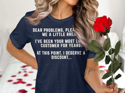 Navy blue t-shirt with white text reading "Dear problems, please give me a little break. I've been your most loyal customer for years. At this point, I deserve a discount..."