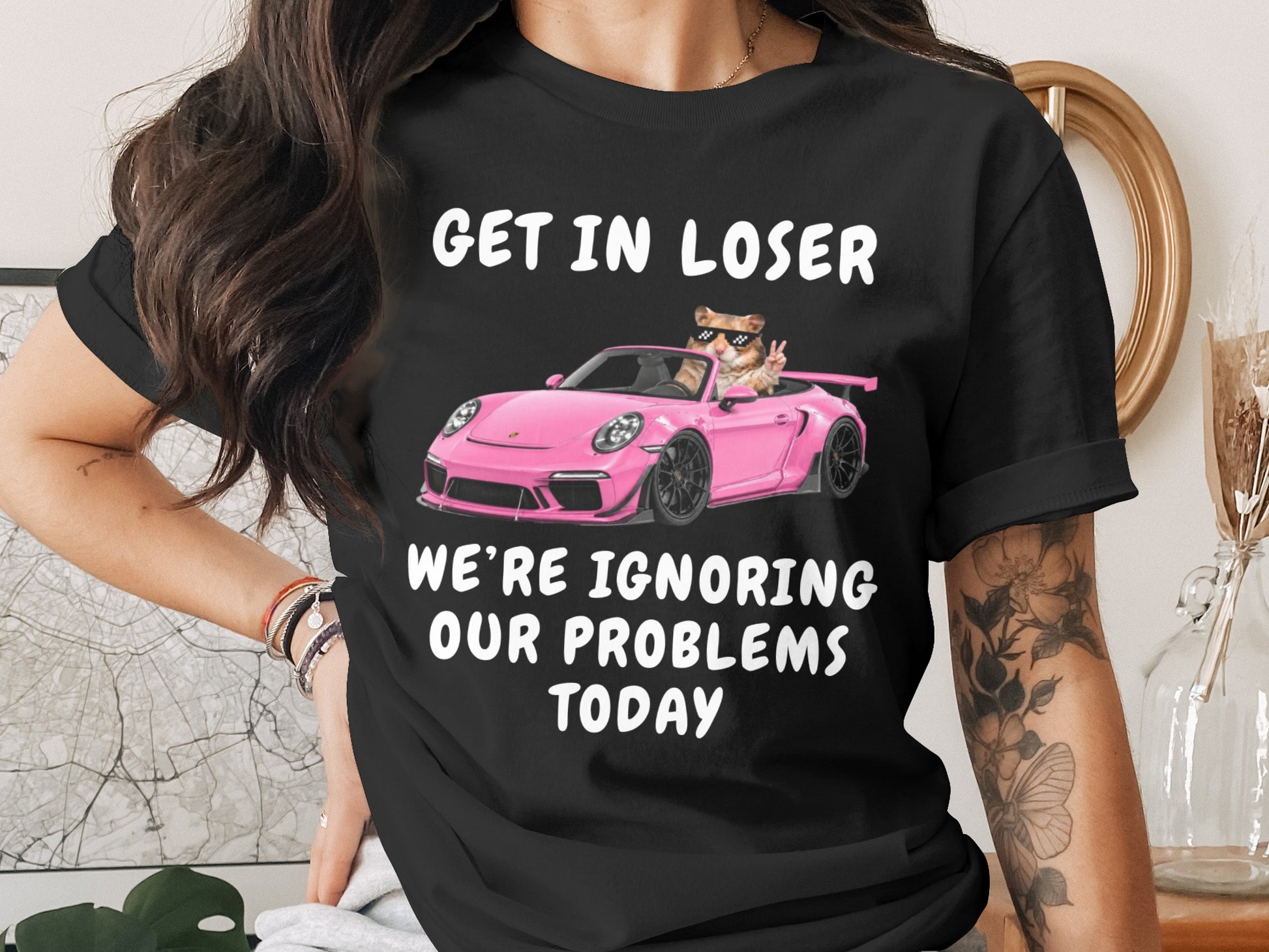 Black t-shirt with text "GET IN LOSER WE'RE IGNORING OUR PROBLEMS TODAY" and a hamster in a pink car.