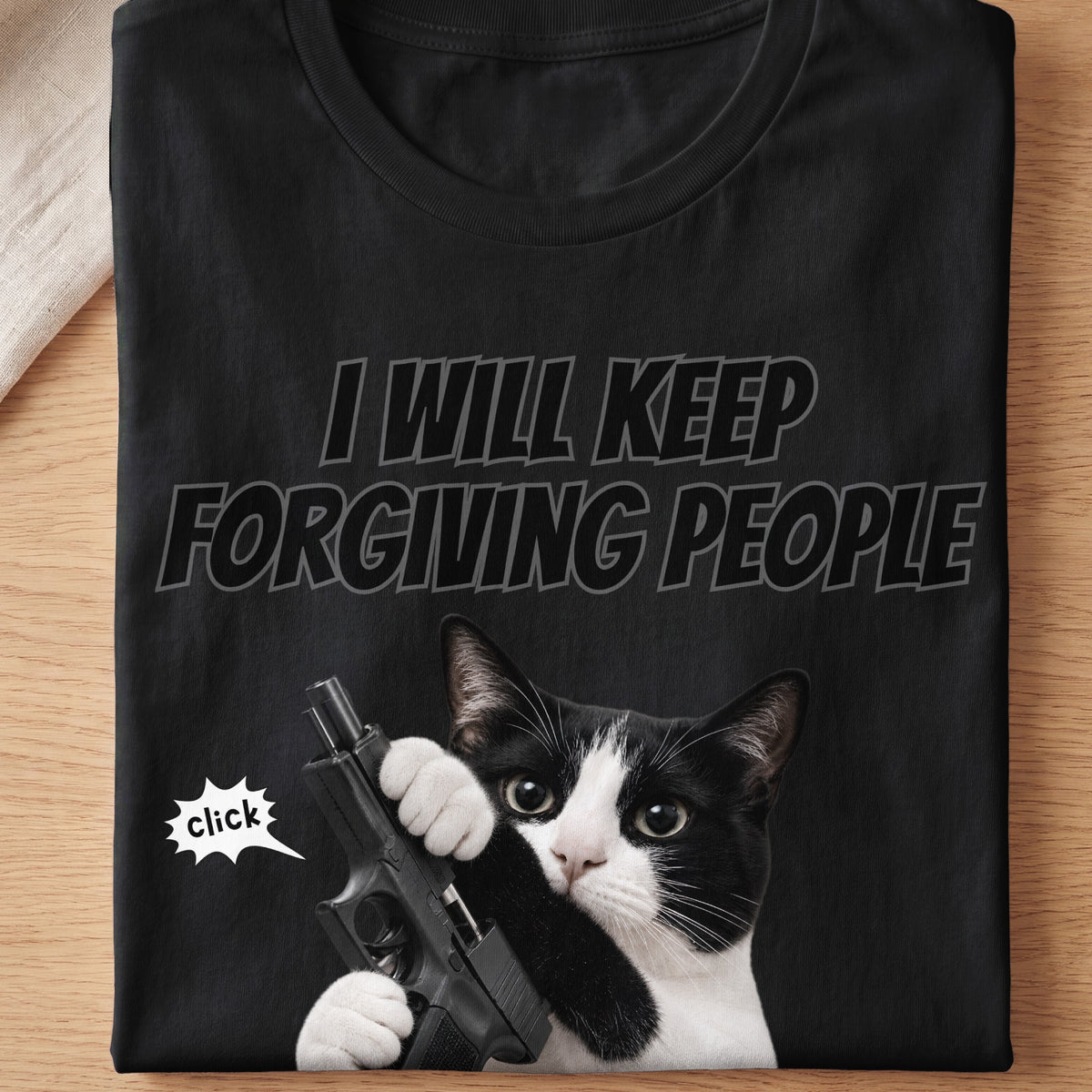 Black t-shirt with a cat holding a gun and text "I will keep forgiving people."