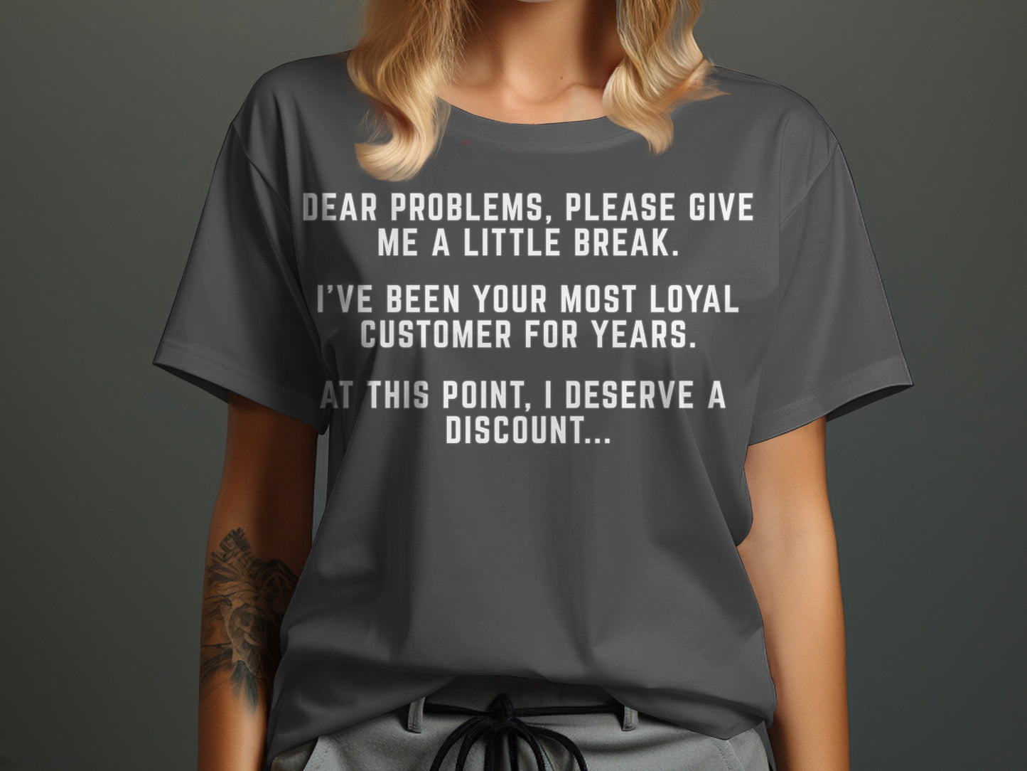 Dark gray t-shirt with white text reading "Dear problems, please give me a little break. I've been your most loyal customer for years. At this point, I deserve a discount..."