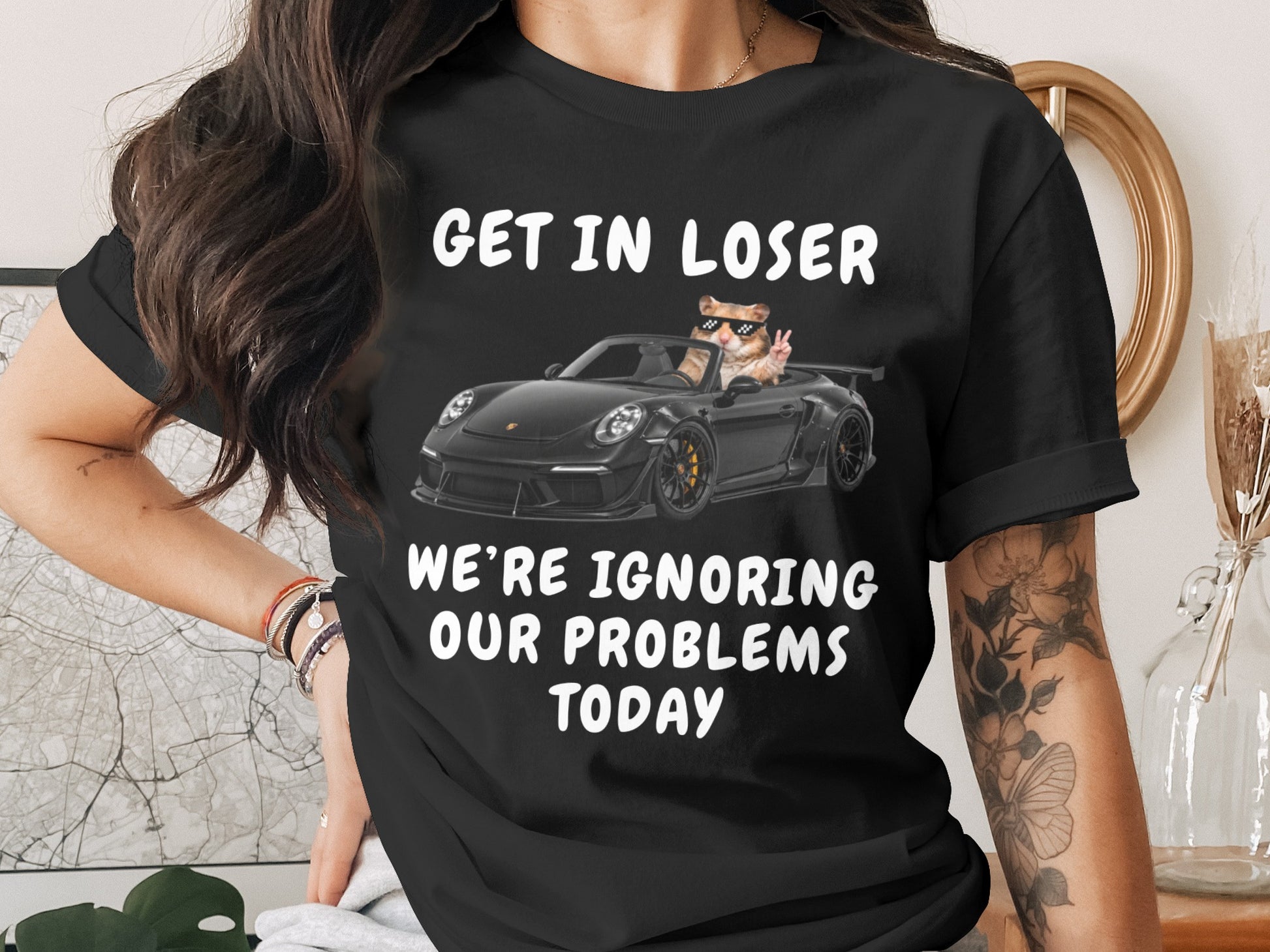 Black t-shirt with "GET IN LOSER WE'RE IGNORING OUR PROBLEMS TODAY" and hamster in car.