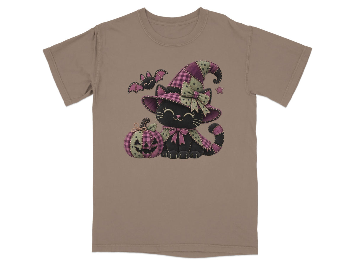 Black cat in witch hat with pumpkin and bat on taupe t-shirt.