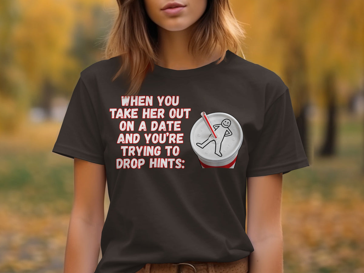 Dark t-shirt with red text: "WHEN YOU TAKE HER OUT ON A DATE AND YOU'RE TRYING TO DROP HINTS:" and a soda cup.