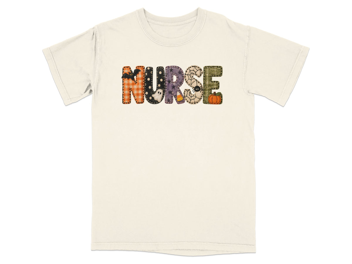 A cream-colored short-sleeved t-shirt featuring the word NURSE spelled out in patterned Halloween-themed block letters.
