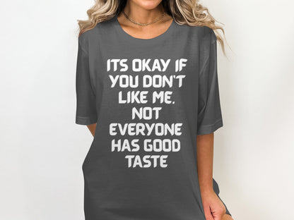 Dark grey t-shirt with white text "ITS OKAY IF YOU DON'T LIKE ME. NOT EVERYONE HAS GOOD TASTE".