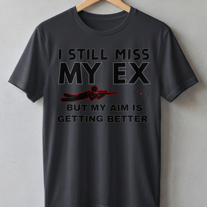 Dark grey t-shirt with "I STILL MISS MY EX BUT MY AIM IS GETTING BETTER" text.