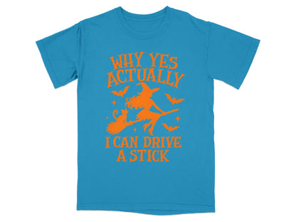 Blue t-shirt with orange graphic: witch on broom, cat, bats, and text "Why Yes Actually I Can Drive A Stick".