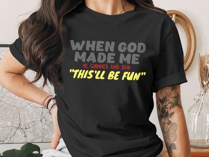 Black t-shirt with text: "WHEN GOD MADE ME HE GRINNED AND SAID 'THIS'LL BE FUN'".