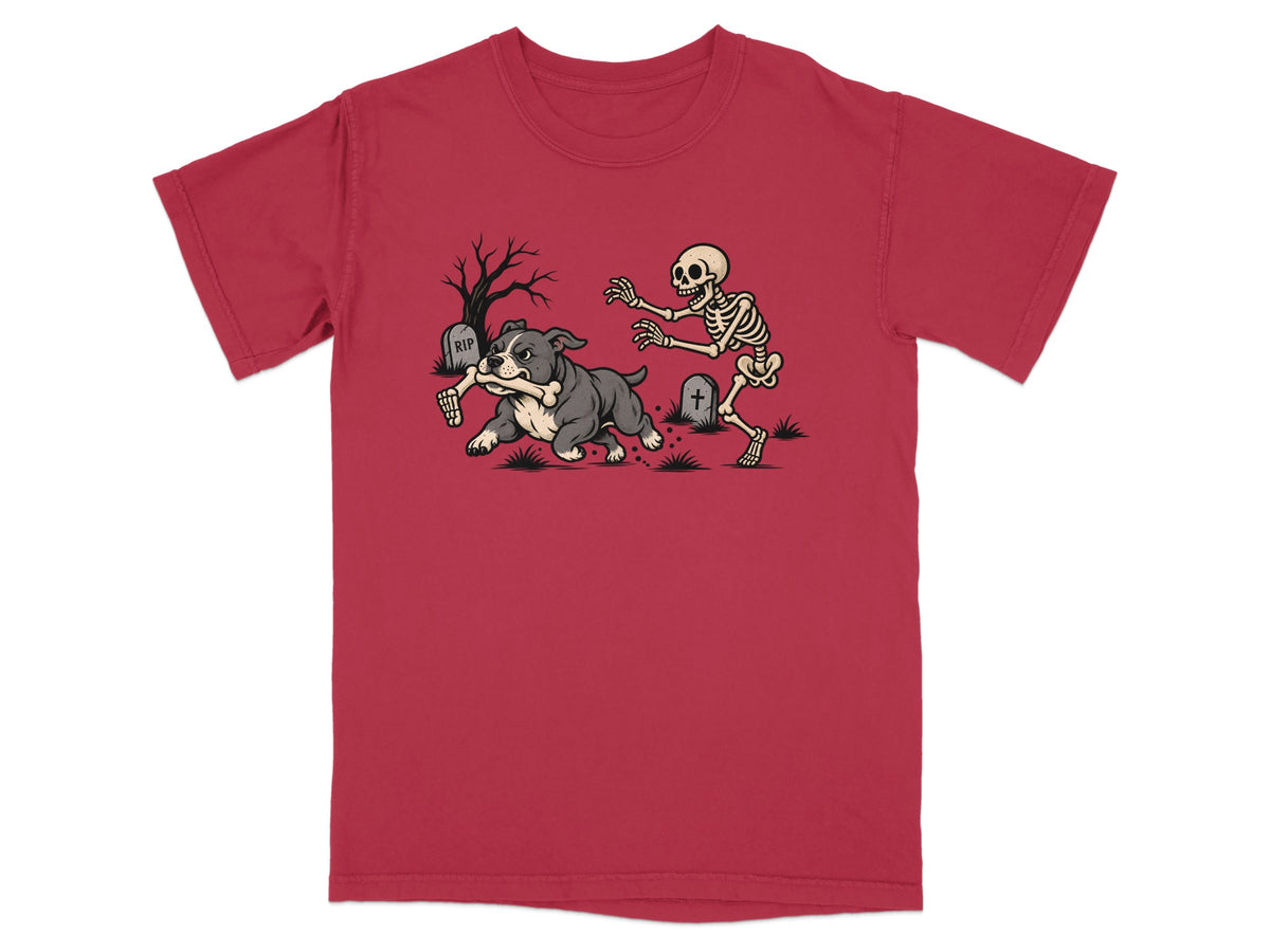 A red t-shirt featuring a graphic of a bulldog running away from an angry skeleton.