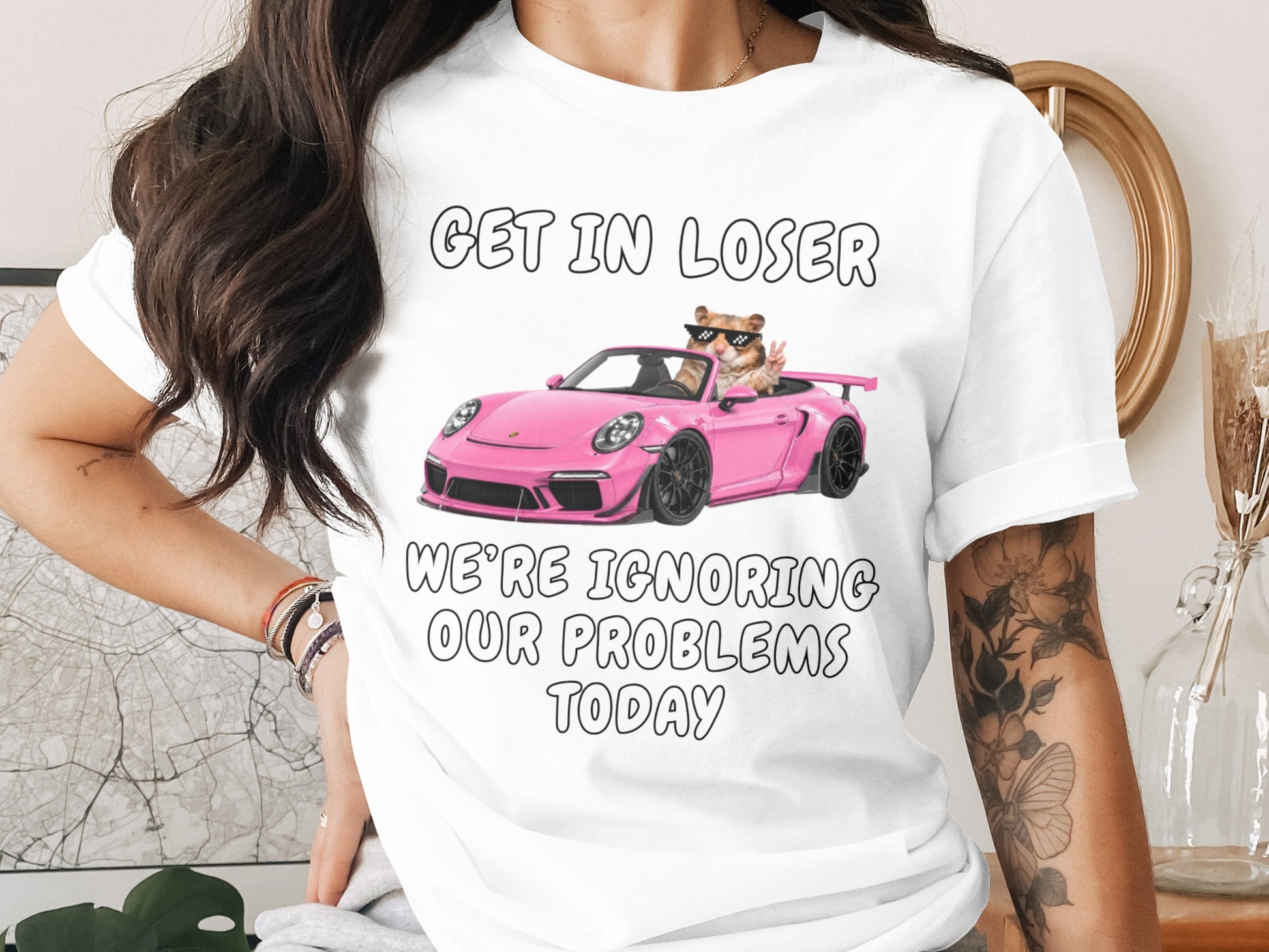T-shirt with text "GET IN LOSER WE'RE IGNORING OUR PROBLEMS TODAY" and a hamster driving a pink car.