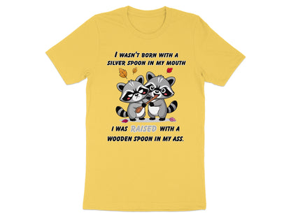 Yellow t-shirt with raccoons and text: "I wasn't born with a silver spoon in my mouth. I was raised with a wooden spoon in my ass."