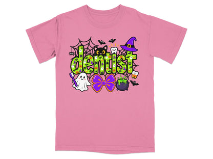 Pink t-shirt with a green Halloween graphic reading dentist, surrounded by ghosts, cats, and witch hats.