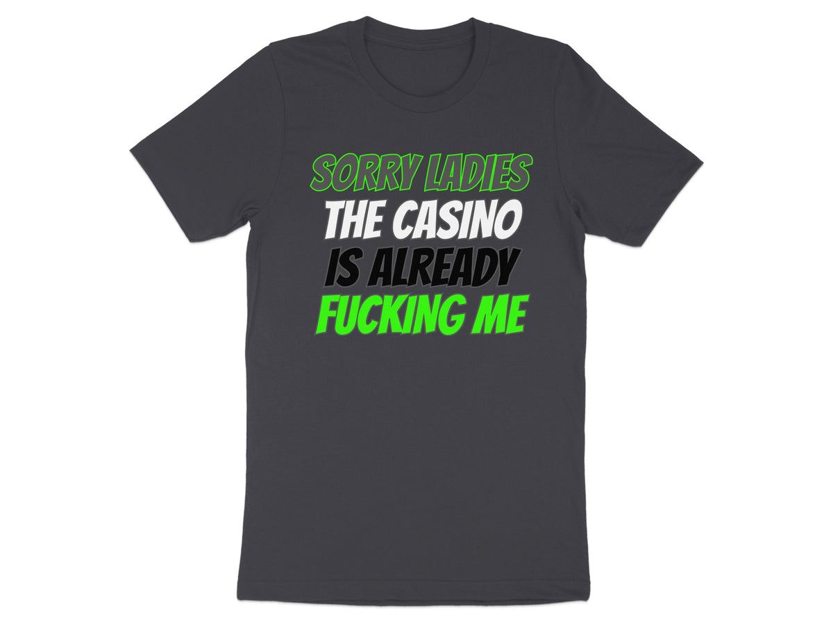 Dark grey t-shirt with text: "SORRY LADIES THE CASINO IS ALREADY FUCKING ME".