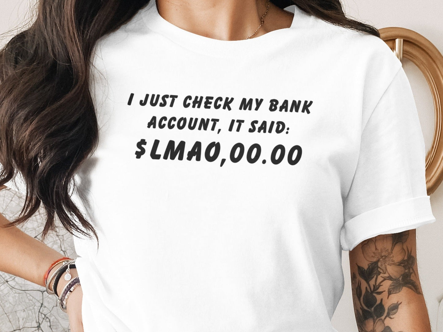 White t-shirt with black text: "I JUST CHECK MY BANK ACCOUNT, IT SAID: $LMAO,00.00"