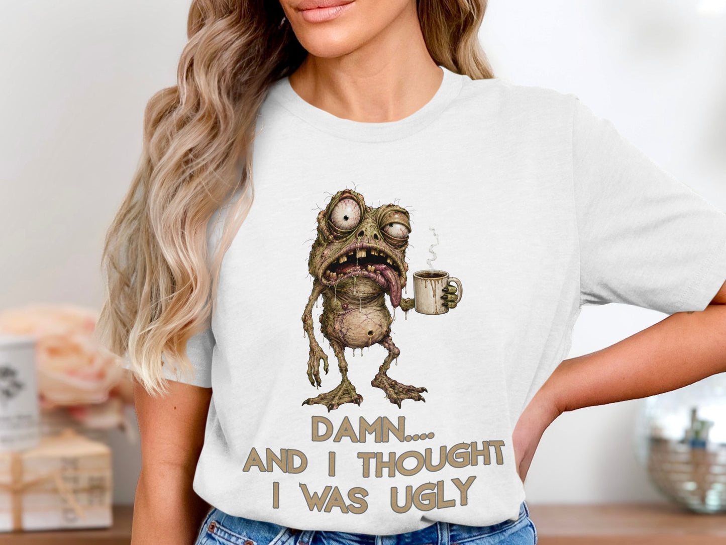 White t-shirt with a cartoon monster holding coffee and text that reads "Damn... and I thought I was ugly."