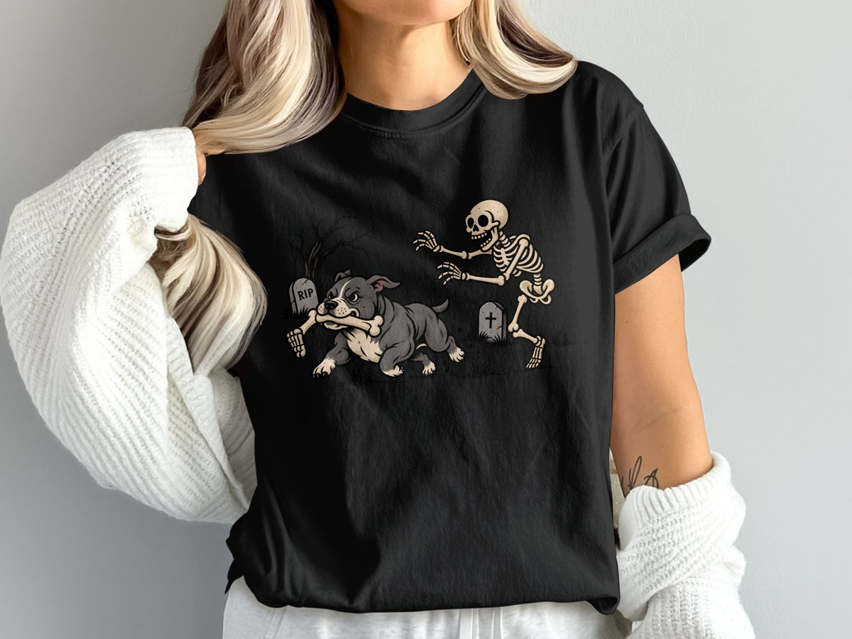 A woman wearing a black t-shirt printed with a graphic of a skeleton chasing a dog carrying a bone.