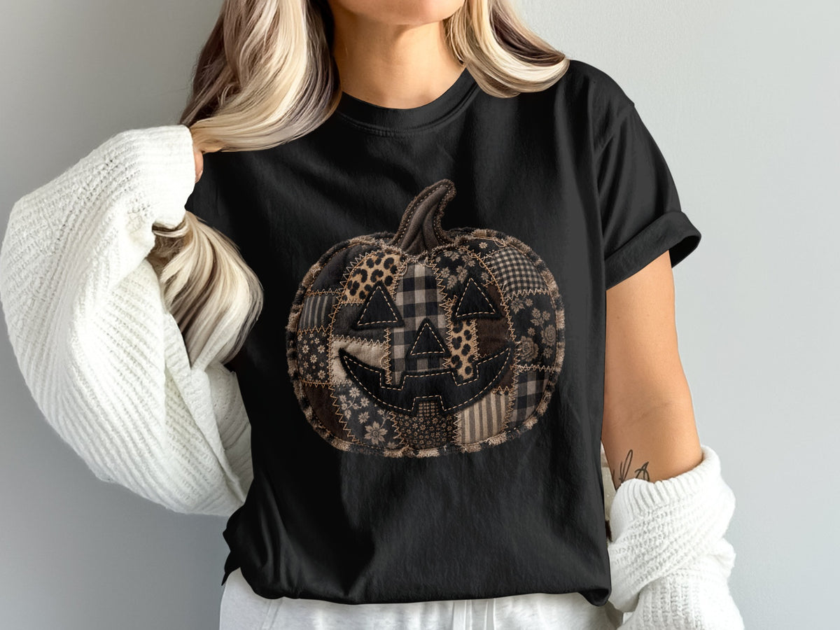 Black t-shirt with a patchwork jack-o'-lantern graphic featuring various fall patterns.