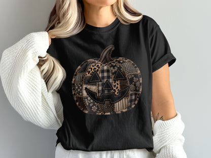 Black t-shirt with a patchwork jack-o'-lantern graphic featuring various fall patterns.