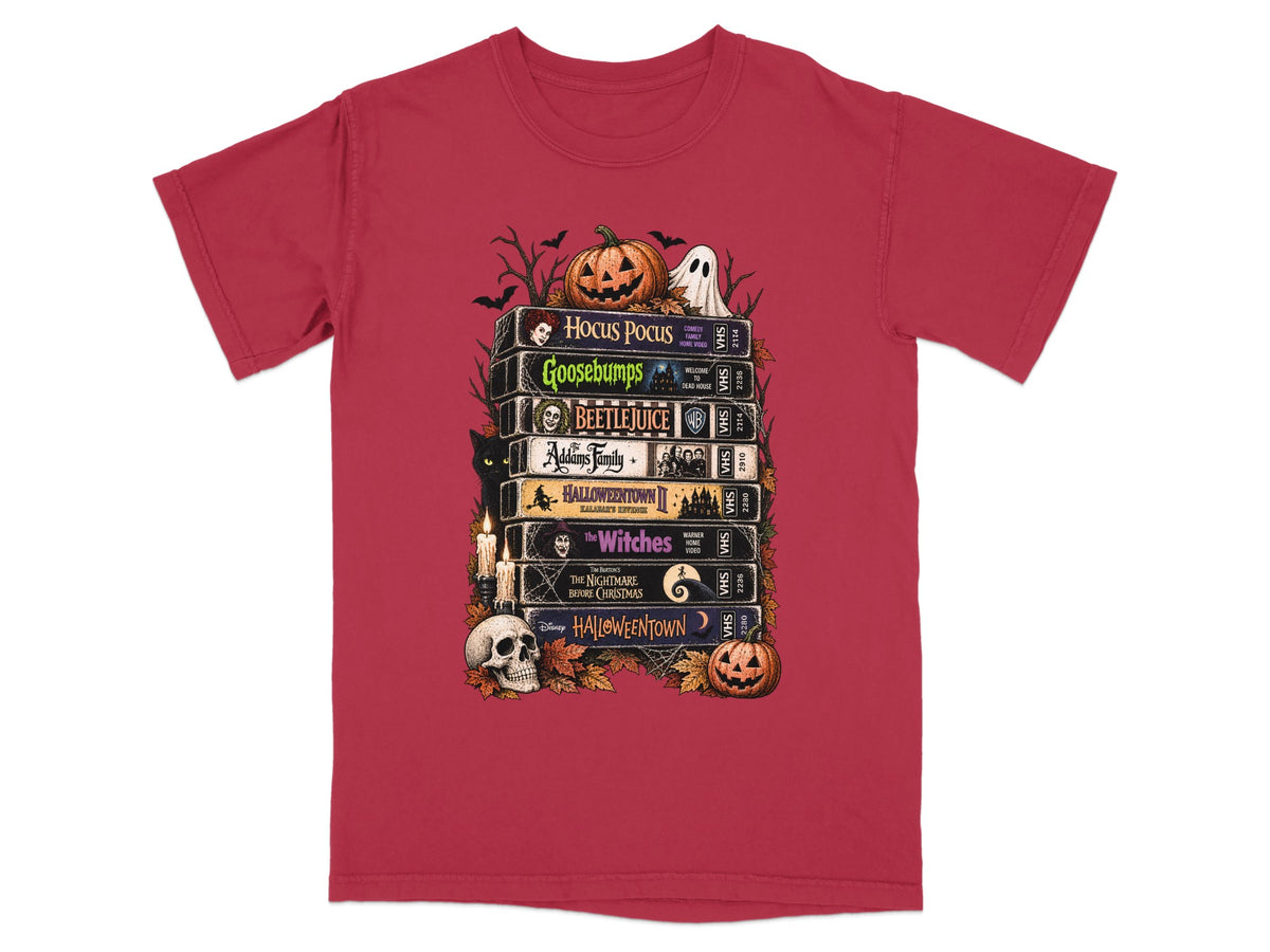 T-shirt graphic of stacked VHS tapes featuring Hocus Pocus, Goosebumps, Beetlejuice, Addams Family, and Halloween Town.