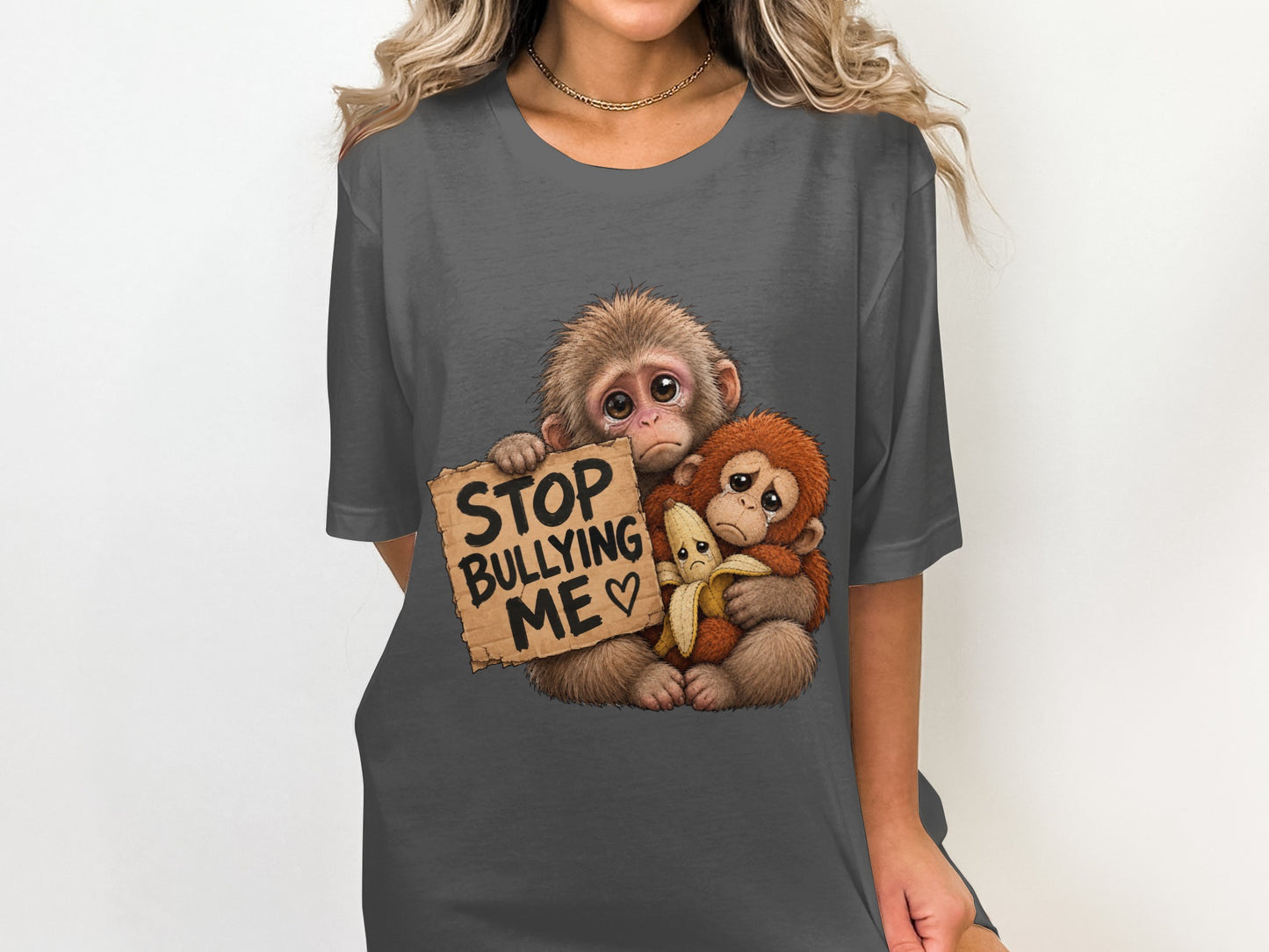 Two sad monkeys hold a sign that says "Stop Bullying Me" with a banana.