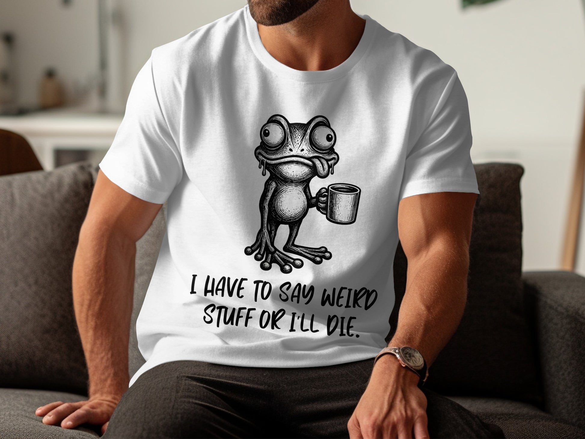 White t-shirt with a black graphic of a frog holding a mug and the text "I HAVE TO SAY WEIRD STUFF OR I'LL DIE."