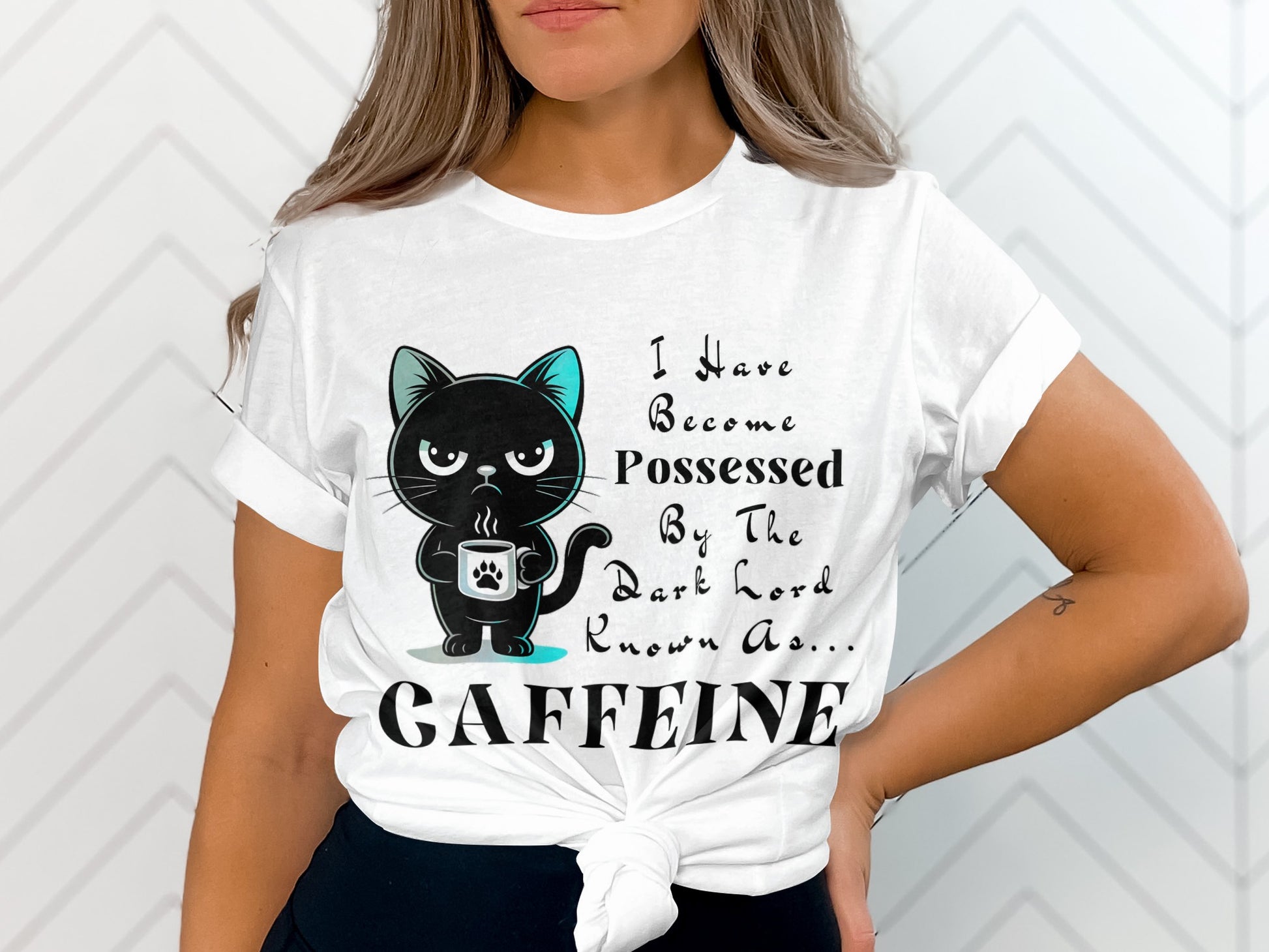 White t-shirt with a black cat holding a coffee mug and text stating "I Have Become Possessed By The Dark Lord Known As... CAFFEINE."