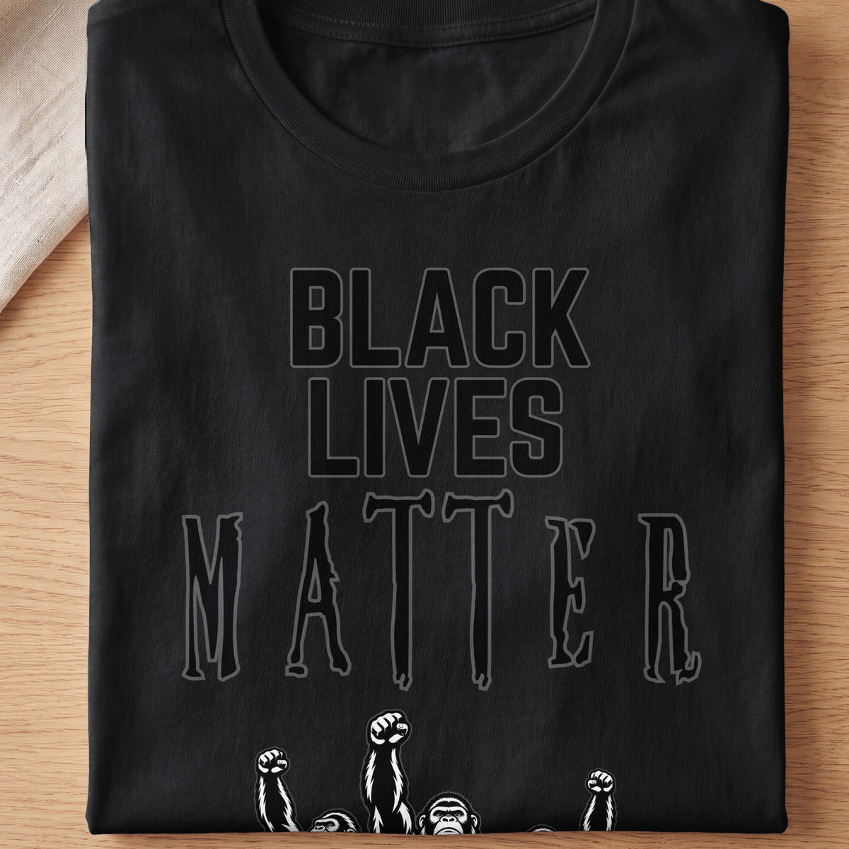 Black Lives Matter text with raised fists and ape faces on black t-shirt.