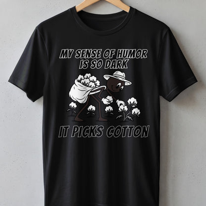 Black t-shirt with cartoon character picking cotton, text reads "MY SENSE OF HUMOR IS SO DARK IT PICKS COTTON".