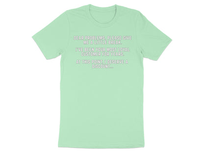 Light green t-shirt with text "Dear problems, please give me a little break. I've been your most loyal customer for years. At this point, I deserve a discount...".