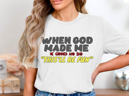 White t-shirt with text: WHEN GOD MADE ME HE GRINNED AND SAID "THIS'LL BE FUN".