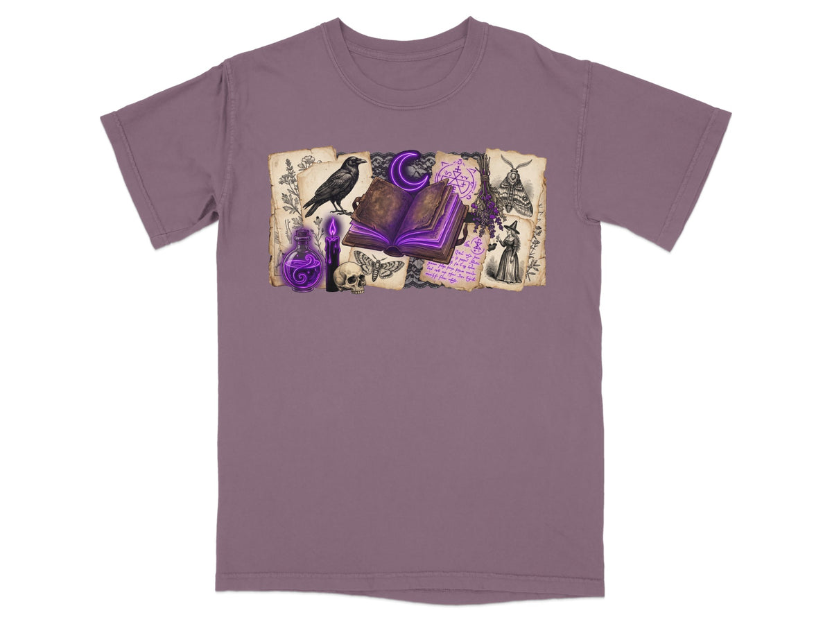 Dark purple t-shirt with witchy graphic featuring open book, raven, skull, and potion.