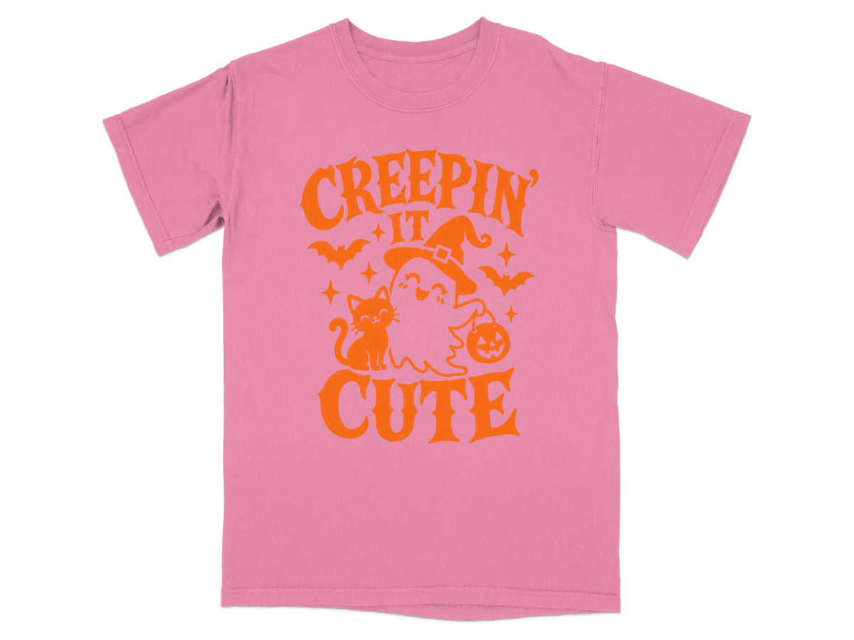 Pink t-shirt with orange Halloween graphic saying "Creepin' It Cute" with ghost, cat, and bats.
