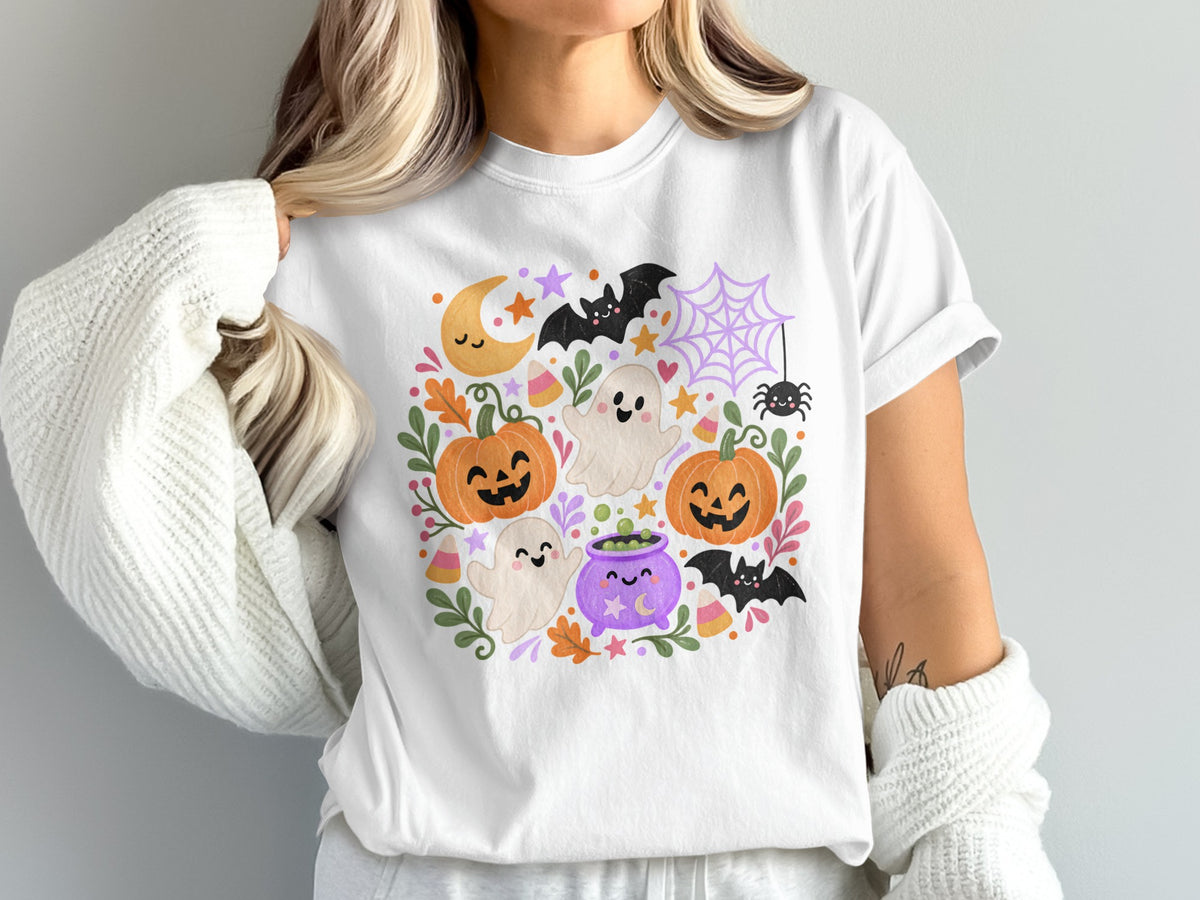 White t-shirt with a Halloween-themed graphic featuring ghosts, pumpkins, bats, and a cauldron.