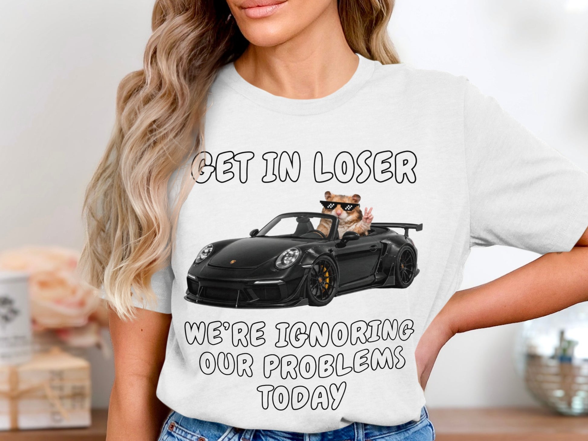 White t-shirt with text "GET IN LOSER WE'RE IGNORING OUR PROBLEMS TODAY" and a hamster driving a car.