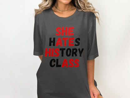 Dark grey t-shirt with "SHE HATES HISTORY CLASS" printed in red and black text.