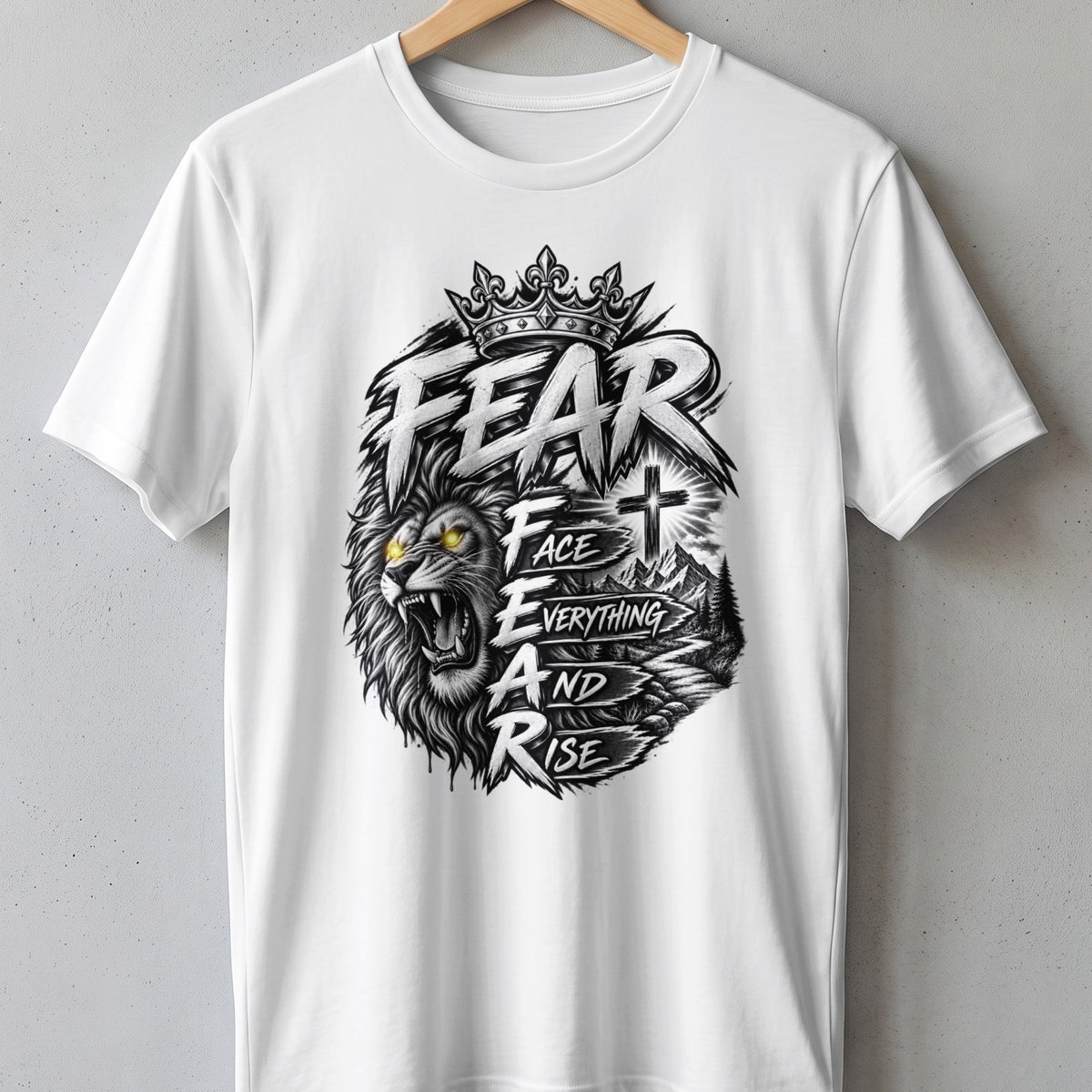 White t-shirt with graphic featuring a lion, crown, cross, mountains, and text "FEAR FACE EVERYTHING AND RISE."