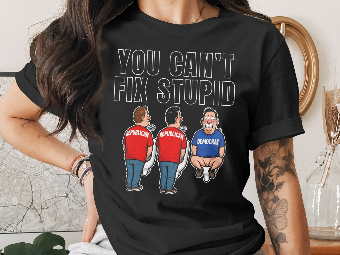 Black t-shirt with "YOU CAN'T FIX STUPID" and cartoon of two Republicans and one Democrat on toilets.