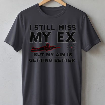 Dark grey t-shirt with text "I STILL MISS MY EX BUT MY AIM IS GETTING BETTER" and sniper graphic.