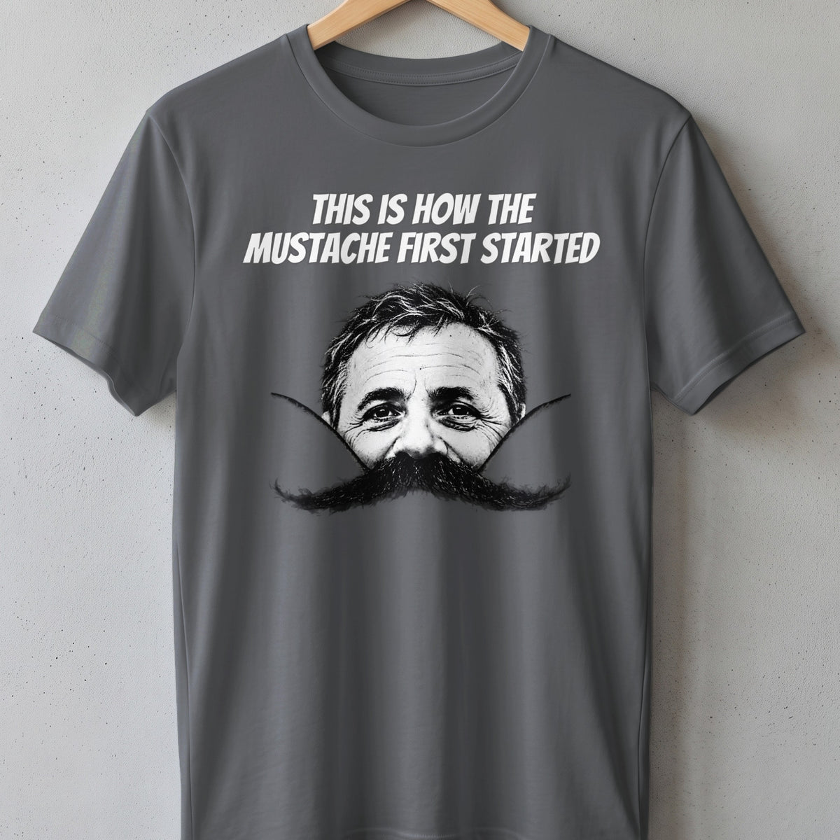 Grey t-shirt with text and a man's face peeking from behind a large mustache.