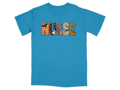 Bright blue short-sleeve t-shirt featuring the word NURSE spelled out in patterned Halloween-themed patches.