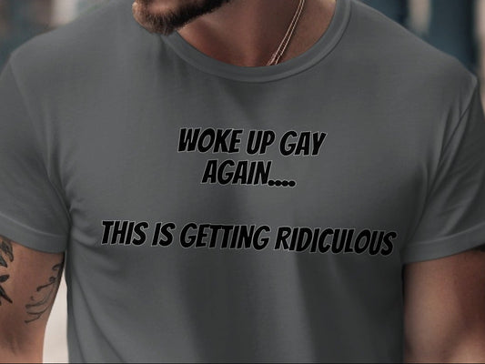Grey t-shirt with black text reading "WOKE UP GAY AGAIN.... THIS IS GETTING RIDICULOUS".