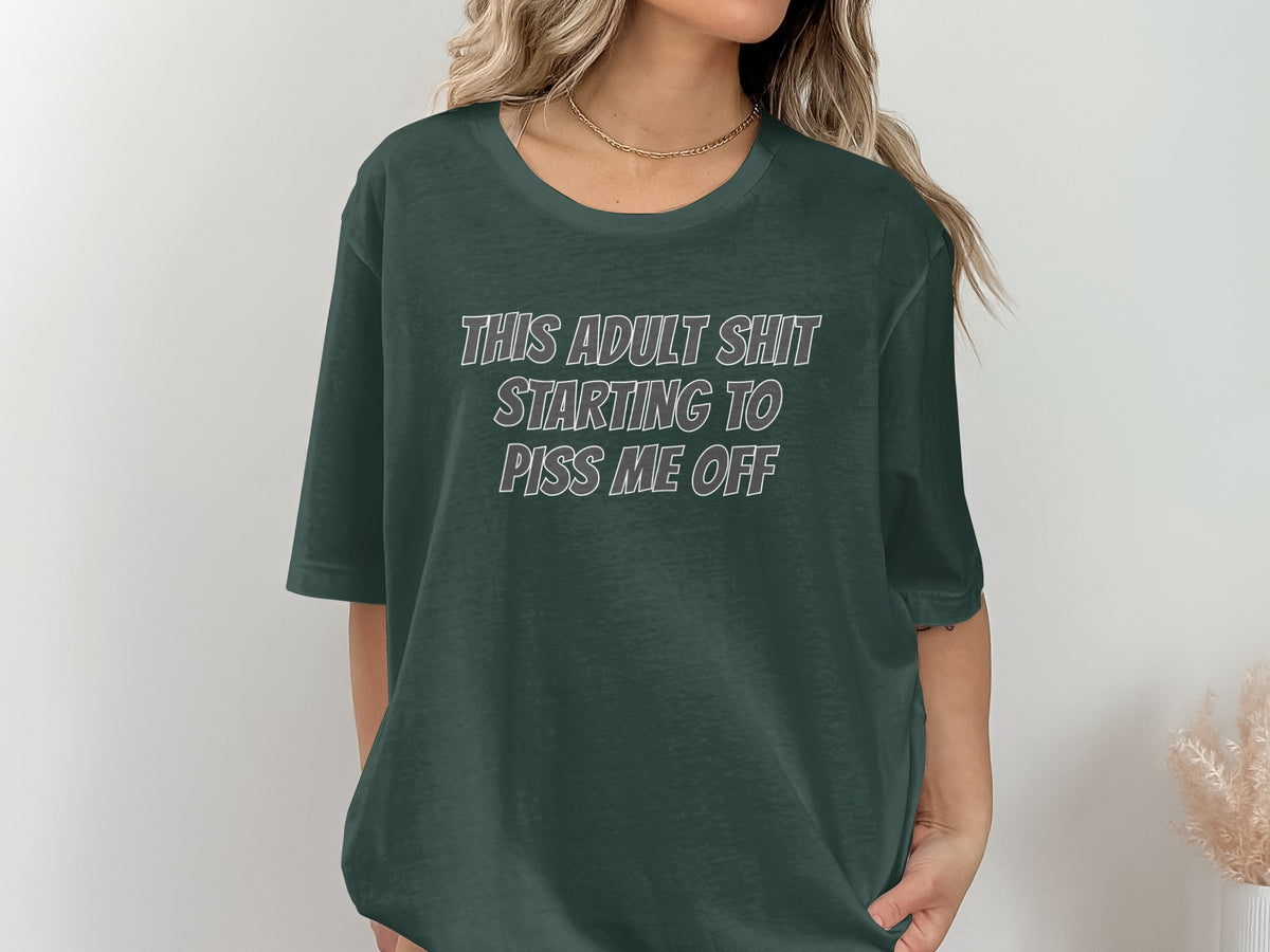 Dark green t-shirt with white text that reads "THIS ADULT SHIT STARTING TO PISS ME OFF".