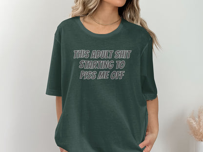 Dark green t-shirt with white text that reads "THIS ADULT SHIT STARTING TO PISS ME OFF".