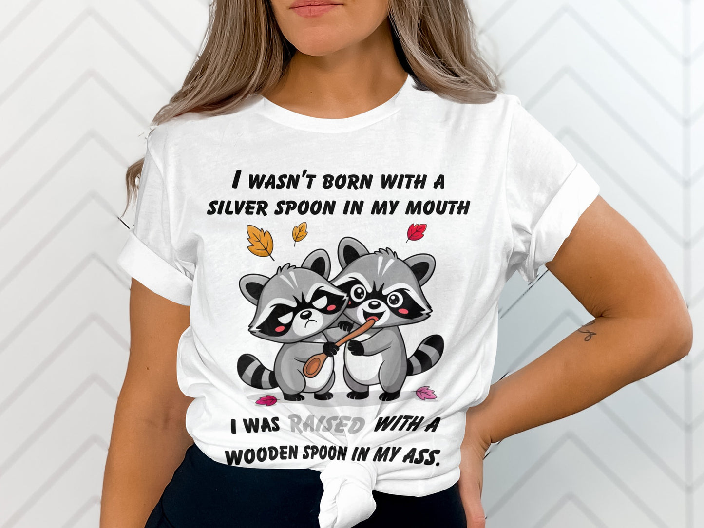 White t-shirt with two raccoons holding a wooden spoon and text.